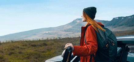 Girl stepping out of car overlooking a beautiful mountain scenery.